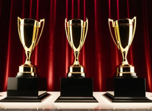 Елегантна церемонія нагородження: сцена з мерехтливими вогнями, абстрактні трофеї на п'єдесталах, святкова атмосфера в розкішному бальному залі готелю. Кінематографічне освітлення, 8k, гіперреалістично.